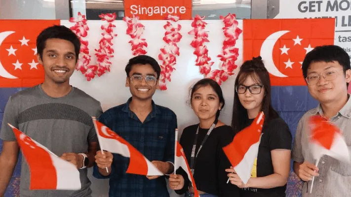 Students smiling and holding Singapore flags.